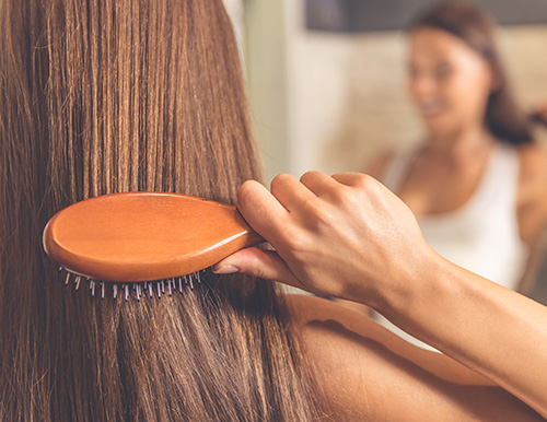 Das Foto zeigt eine Frau, wie sie sich gerade die glatten Haare bürstet